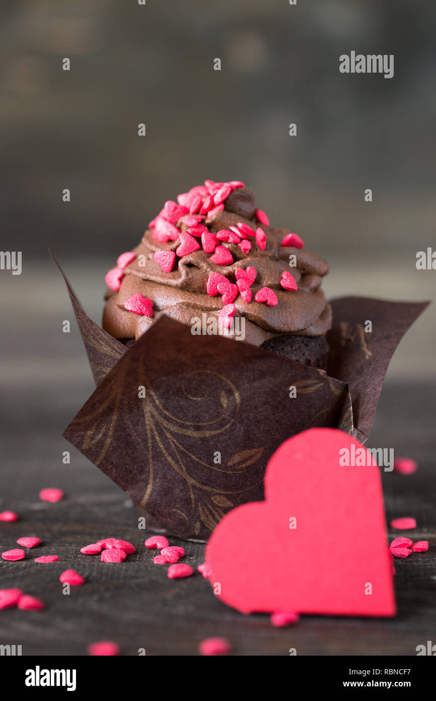 Petit gâteau au chocolat avec crème fouettée, parsemé de coeurs rouges. La cuisson des aliments sucrés pour la Saint-Valentin Banque D'Images