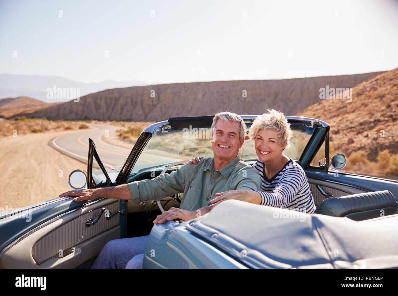 Senior couple sourire à l'appareil photo de garé la voiture à toit ouvert Banque D'Images