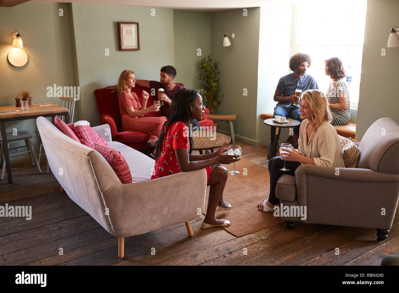 Un groupe de personnes dans un pub boire et parler, pleine longueur Banque D'Images