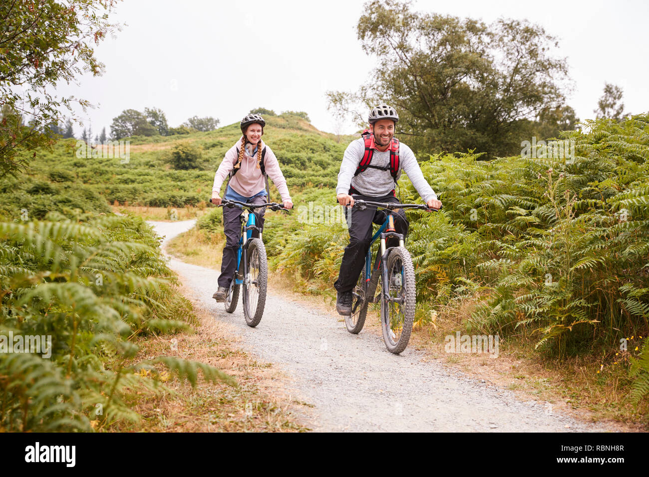 Young adult couple riding mountain bikes dans la campagne, pleine longueur Banque D'Images