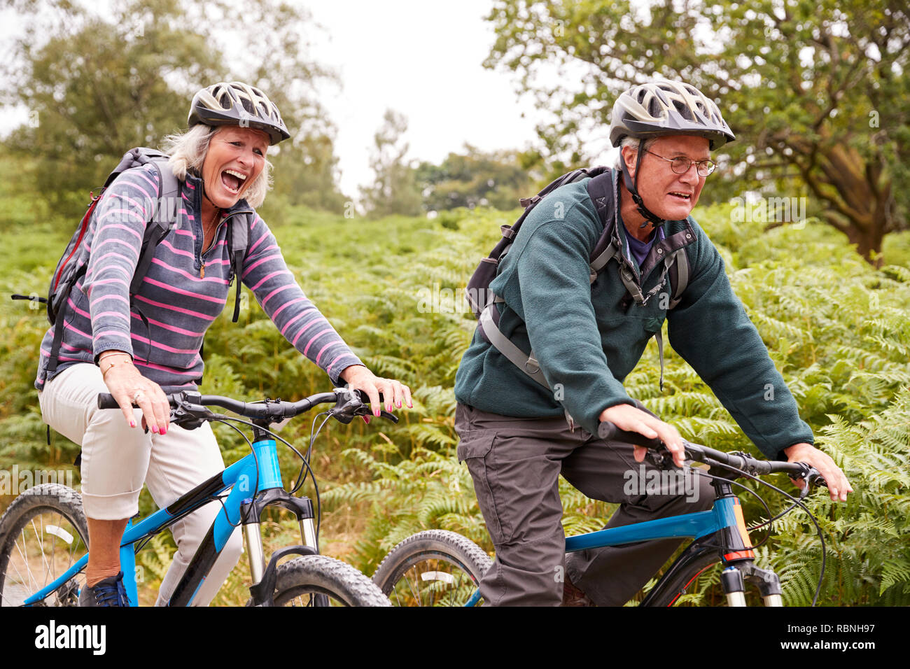 Senior couple riding mountain bikes dans la campagne lors d'une vacances de camping, side view, Close up Banque D'Images