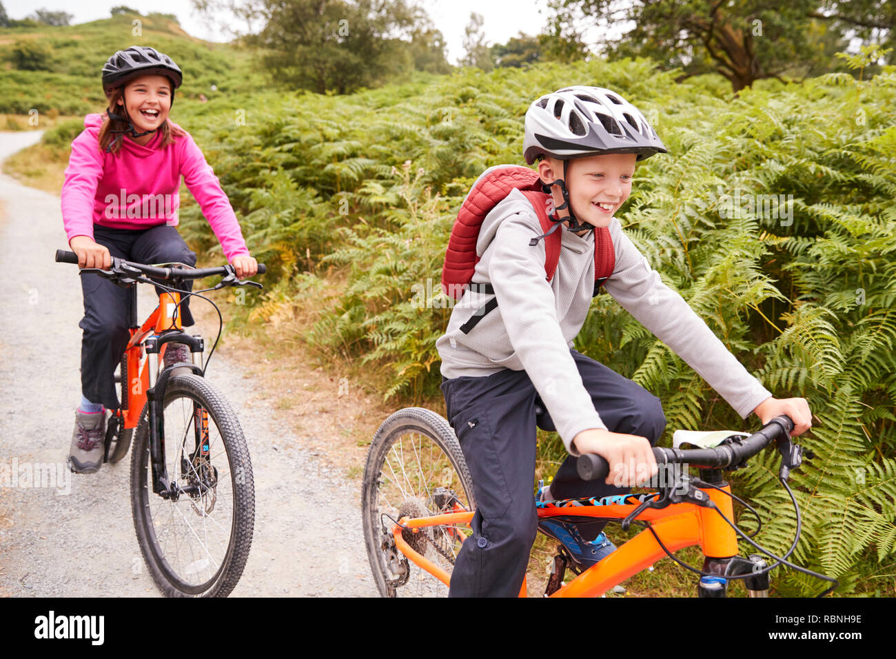 Deux enfants équitation vélo de montagne sur un chemin pays rire, selective focus Banque D'Images