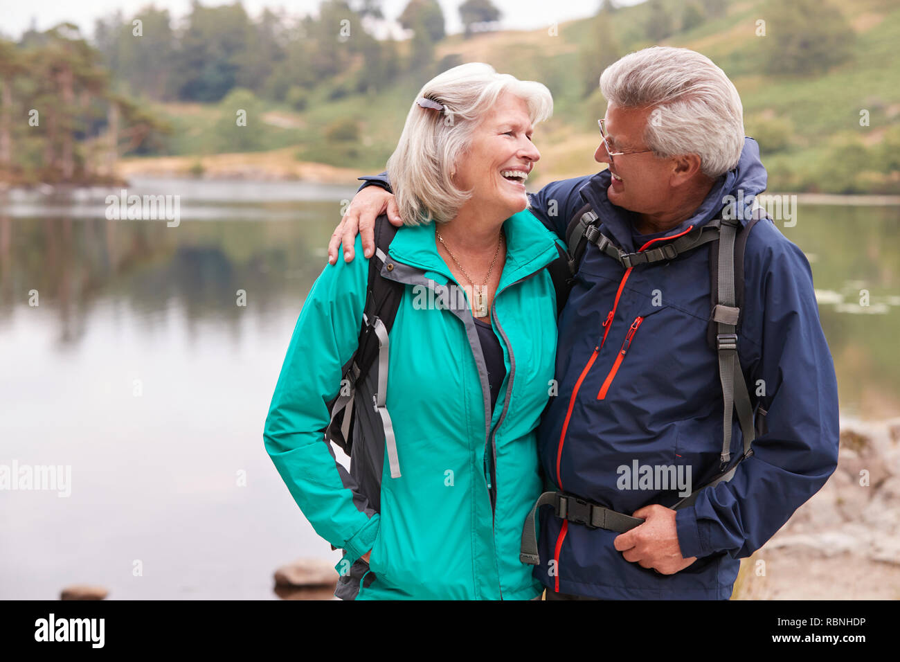 Happy senior couple debout sur une rive d'un lac, Lake District, UK Banque D'Images