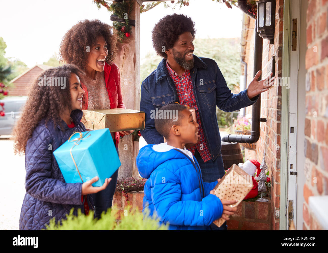 Family Standing At Front Door qu'ils arrivent pour visiter le Jour de Noël avec des Cadeaux Banque D'Images