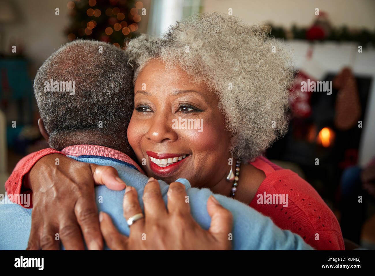 Senior Couple Hugging comme ils célébrer Noël ensemble, à la maison Banque D'Images