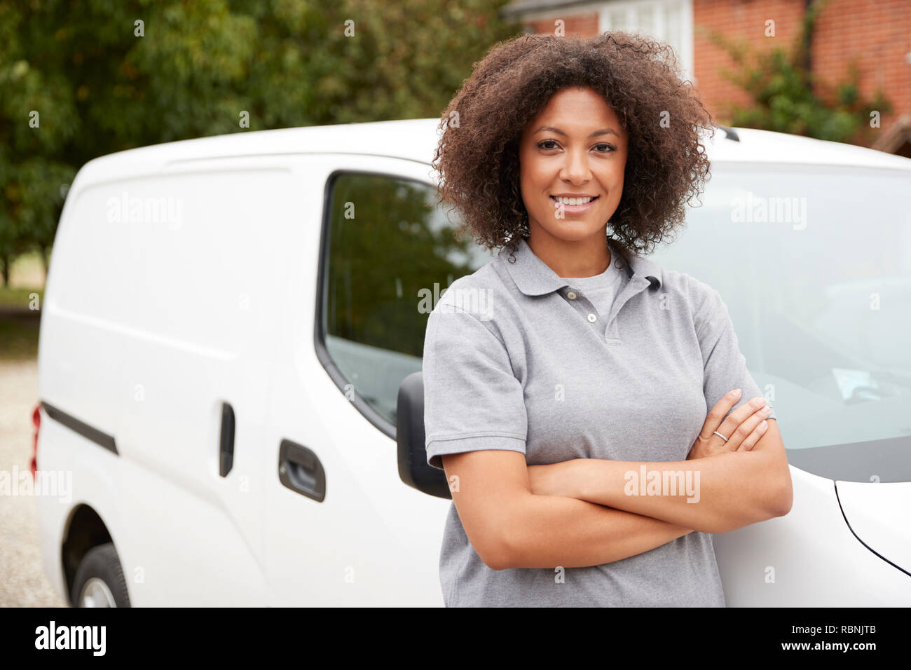 Jeune femme noire de métier debout à côté de sa camionnette blanche avec les bras croisés, Close up Banque D'Images