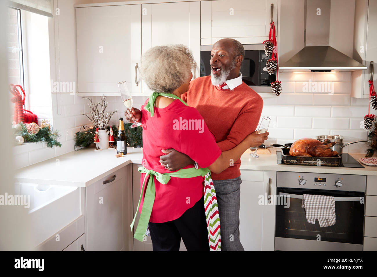Mature black couple holding, rire et embrassant dans la cuisine pendant la préparation de repas le matin de Noël, Close up Banque D'Images