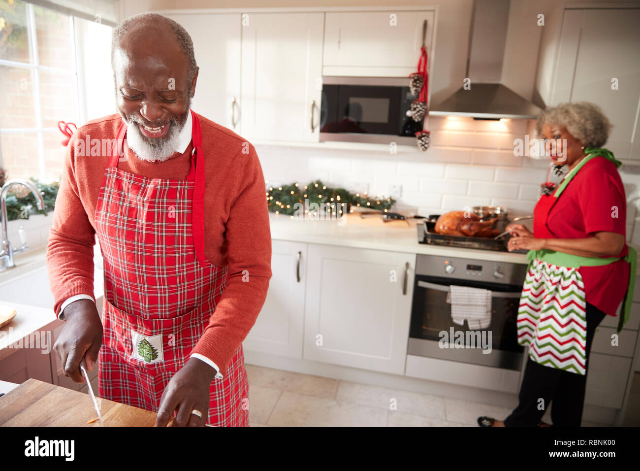 Black mature couple en train de préparer le dîner de Noël, man chopping vegetables au premier plan Banque D'Images