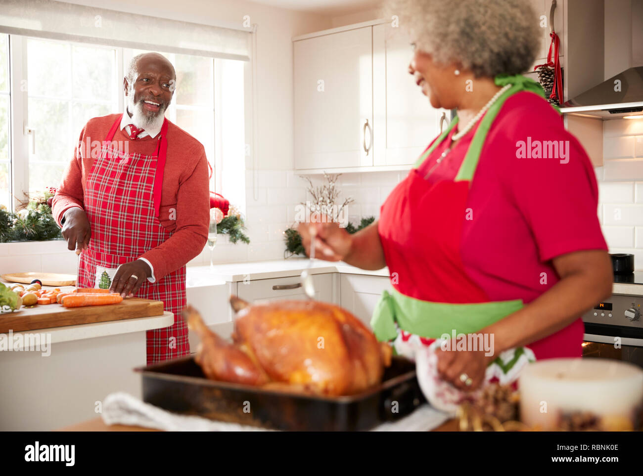 Femme noire de préparer un rôti de dindon pour le dîner de Noël tours de dire à son mari, hacher les légumes dans l'arrière-plan, Close up Banque D'Images