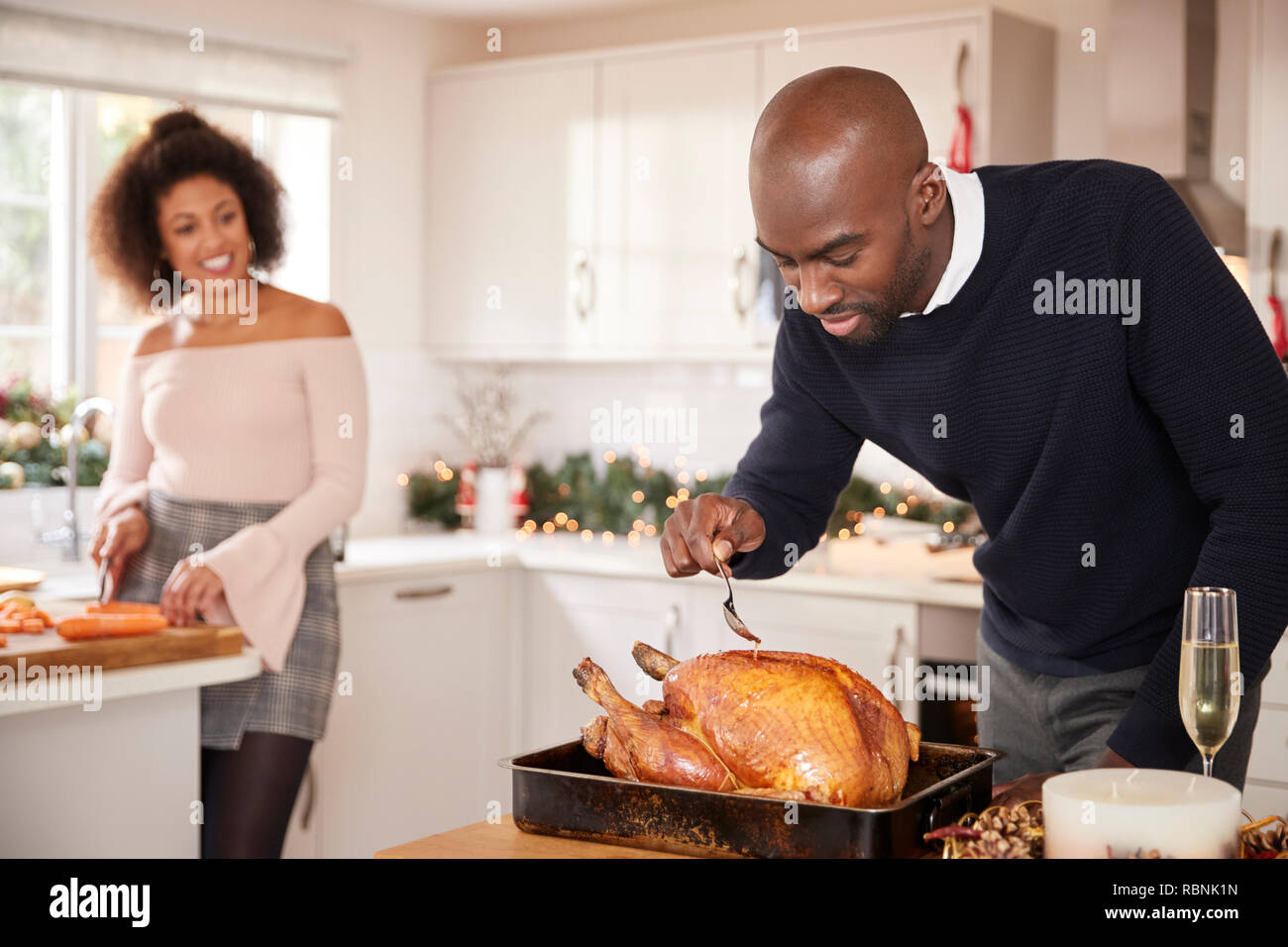 Young adult caucasian couple en train de préparer le dîner de Noël ensemble à la maison, l'homme pour la cuisson de la dinde rôtie au premier plan, Vue de face, Close up Banque D'Images