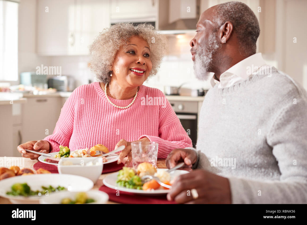 Black Senior couple smiling l'un à l'autre comme ils mangent dimanche soir ensemble à la maison, Close up Banque D'Images