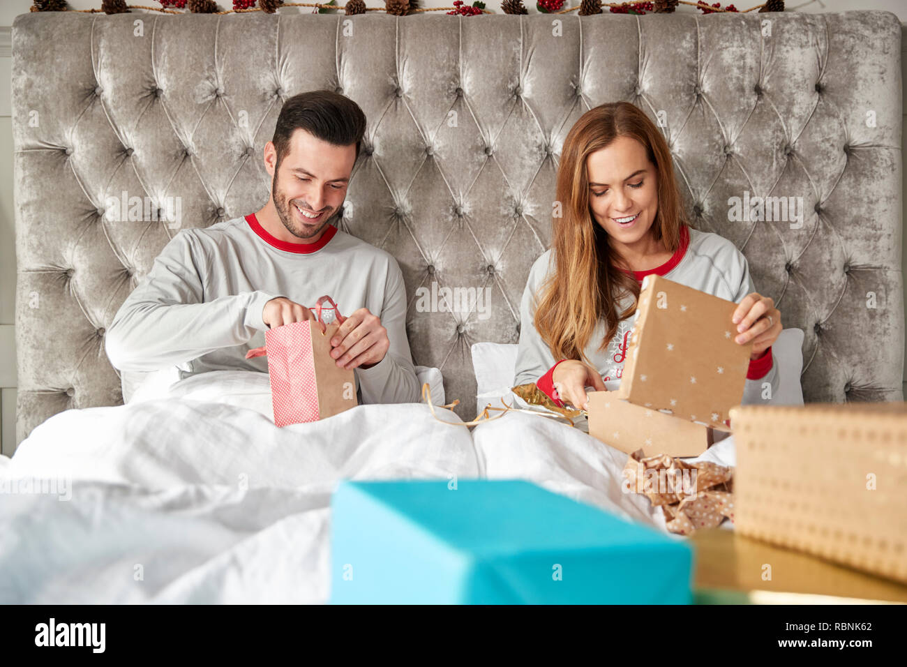 Vue avant du couple au lit à la maison de l'ouverture des cadeaux le jour de Noël Banque D'Images
