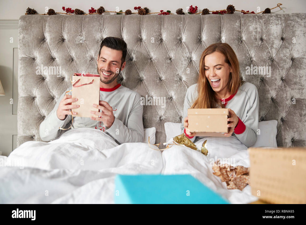 Vue avant du couple au lit à la maison de l'ouverture des cadeaux le jour de Noël Banque D'Images