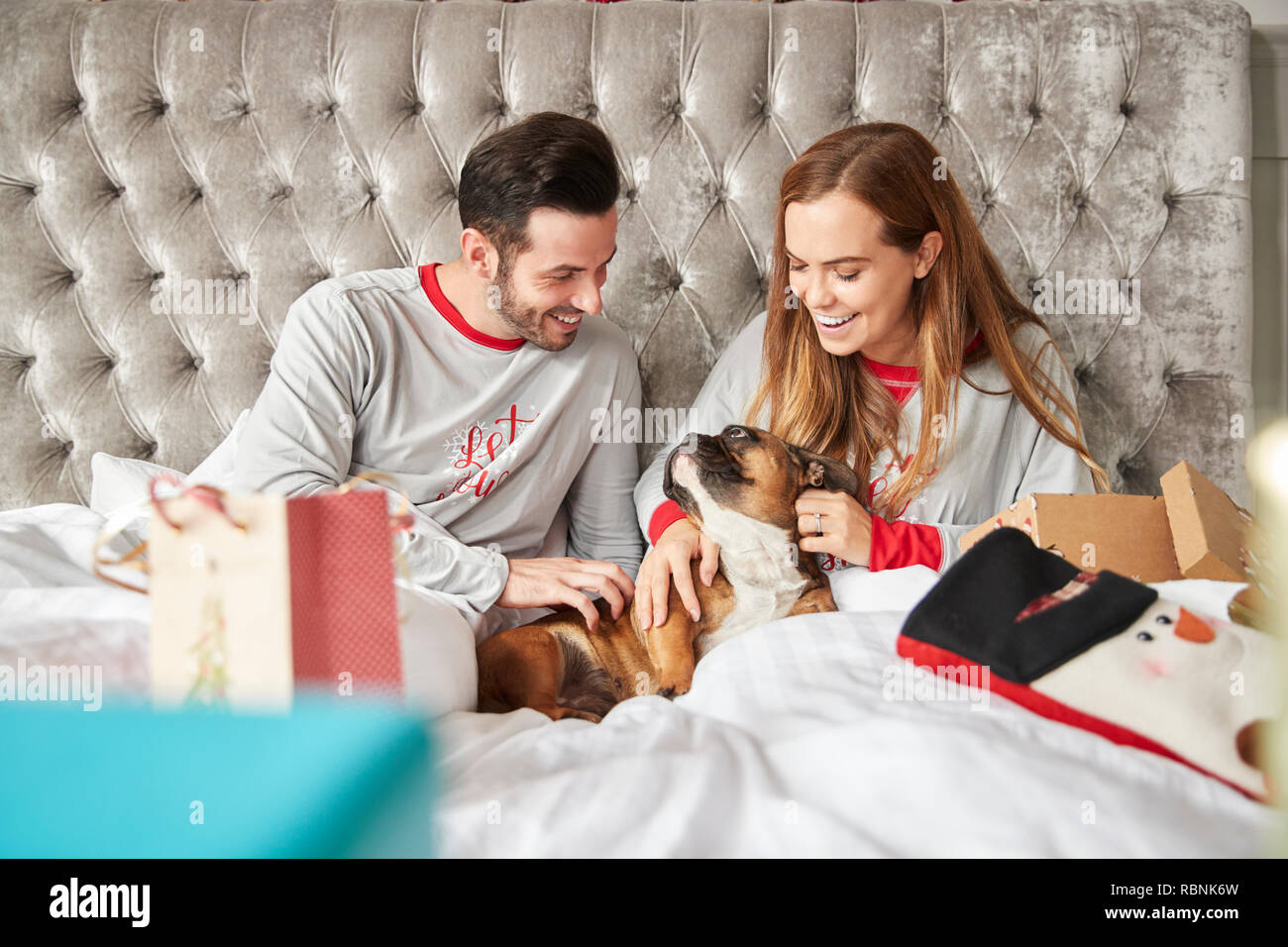Couple au lit à la maison avec le chien Cadeaux Ouverture Costume Le Jour de Noël Banque D'Images