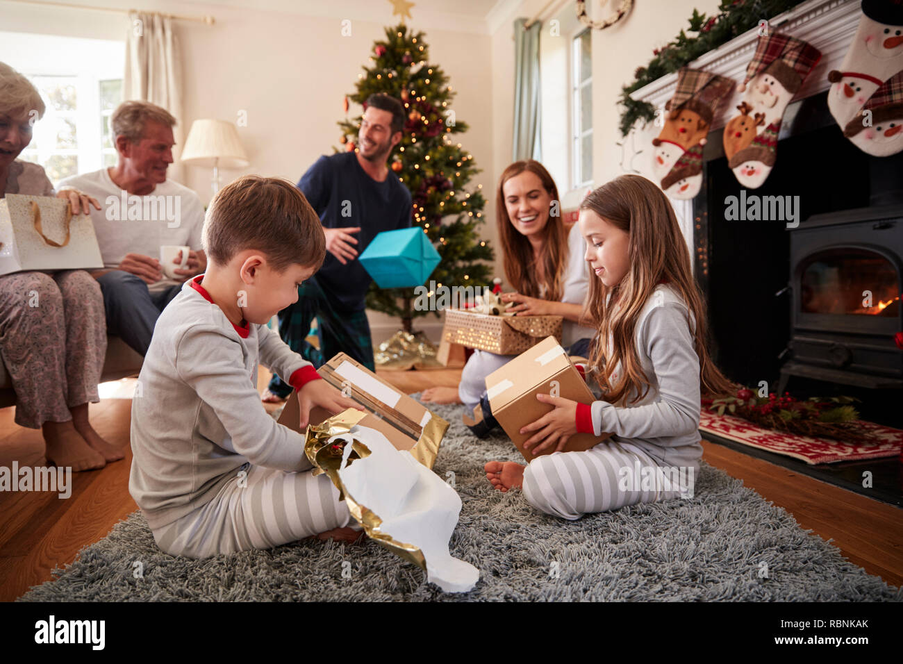 Family Wearing Pajamas dans le salon à la maison de l'ouverture des cadeaux le jour de Noël Banque D'Images