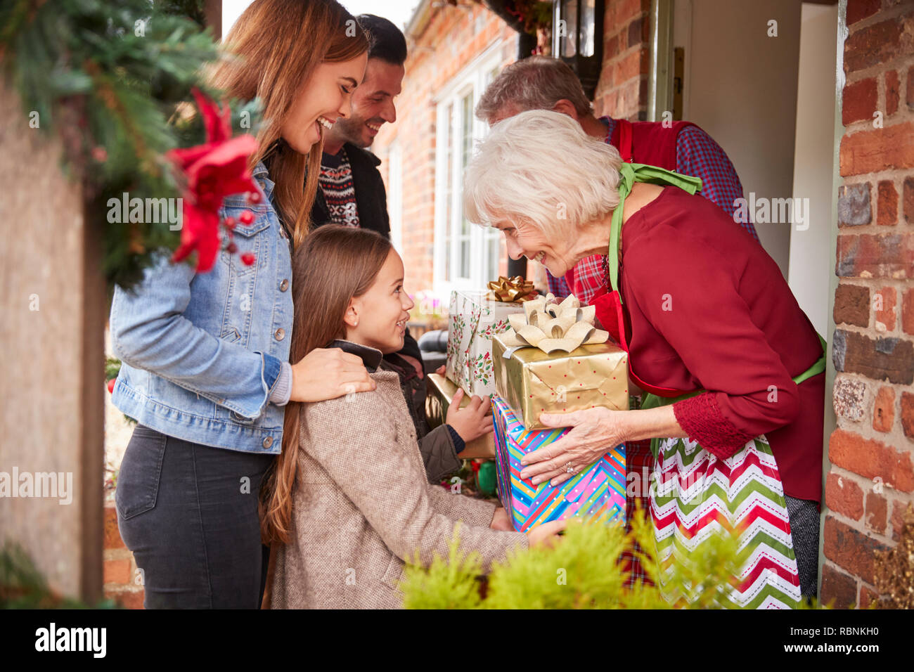 Être accueilli par la famille grands-parents lorsqu'ils arrivent pour visiter le Jour de Noël avec des Cadeaux Banque D'Images