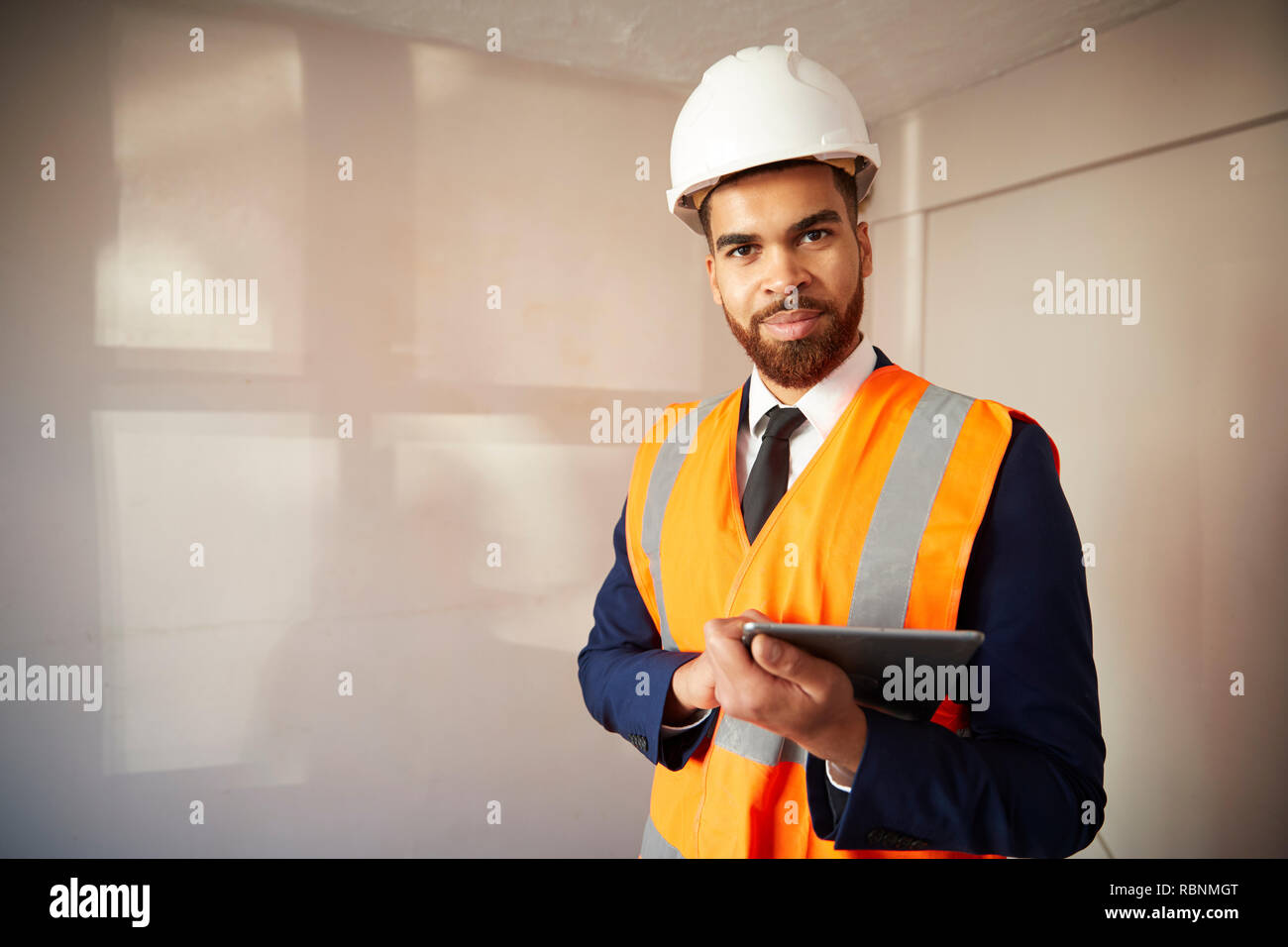 Portrait d'arpenteur en casque et veste haute visibilité avec tablette numérique l'exécution de l'Inspection de la propriété Banque D'Images