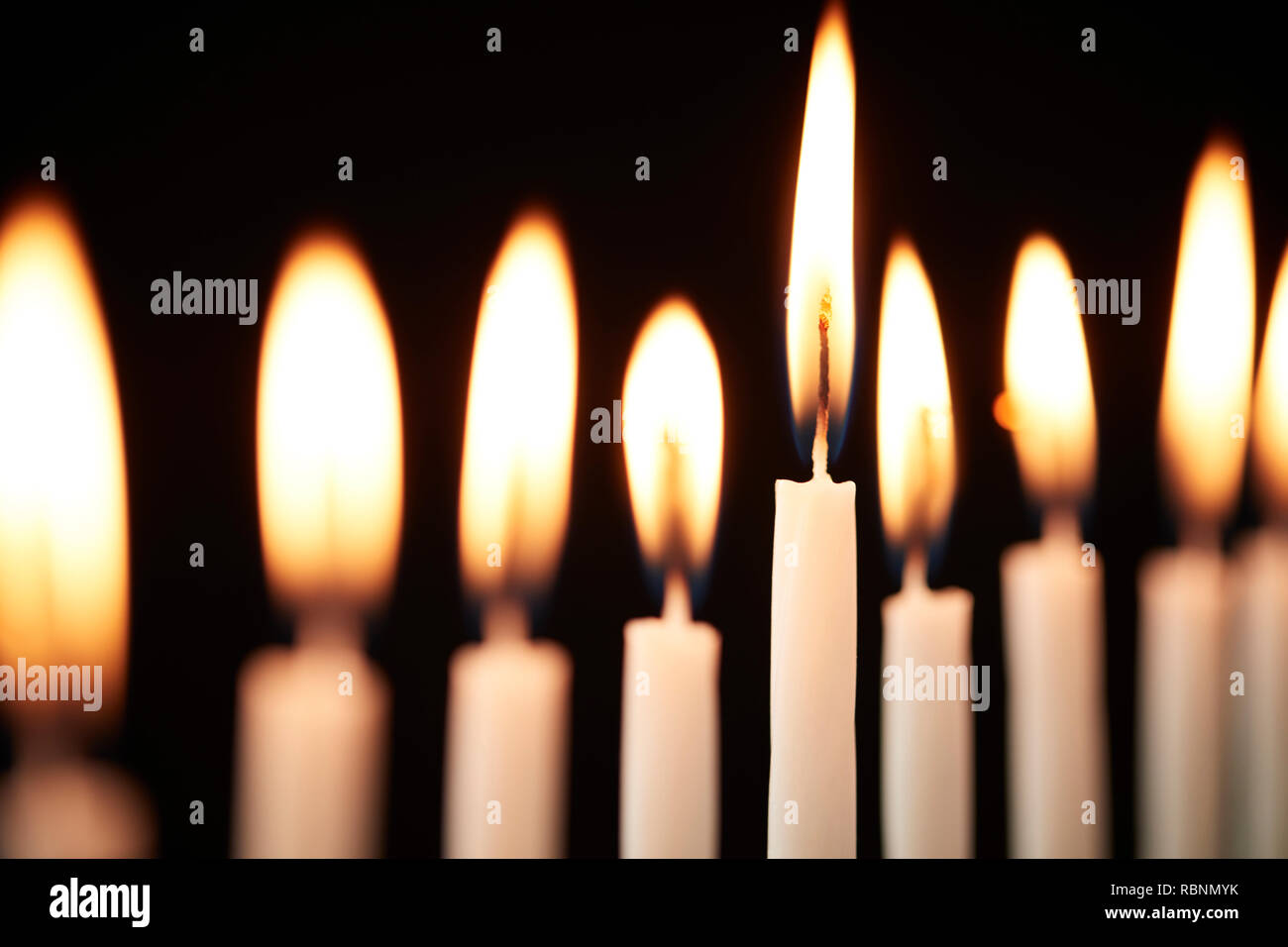 Close Up de bougies allumées sur Metal Hanukkah Menorah contre Black Background Banque D'Images