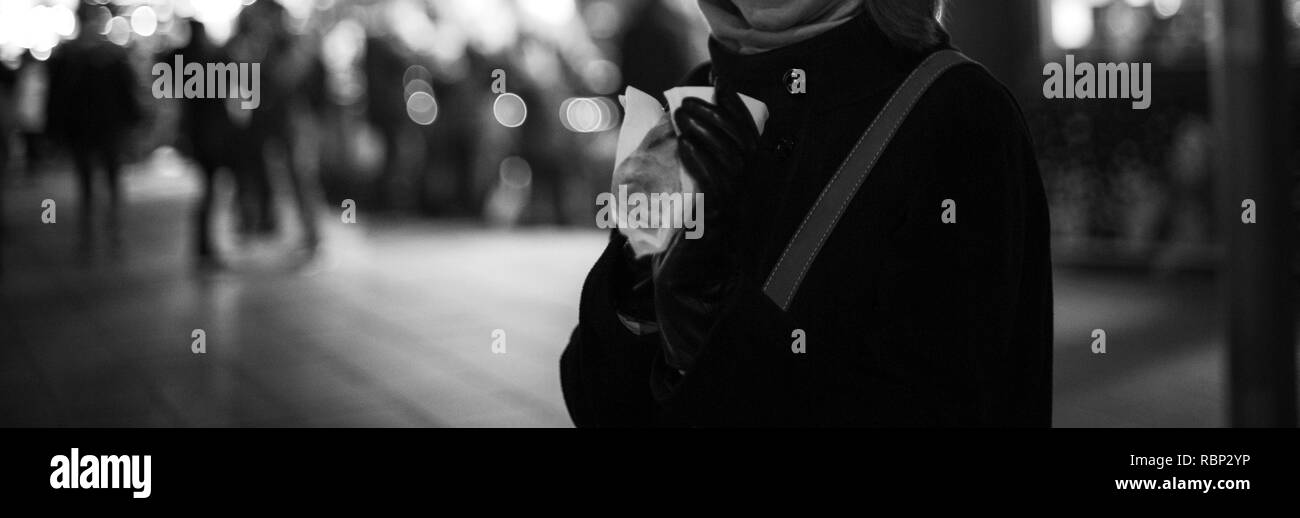 Femme mangeant de la nourriture de Noël traditionnel avec marché de Noël floue de flou artistique en arrière-plan Banque D'Images