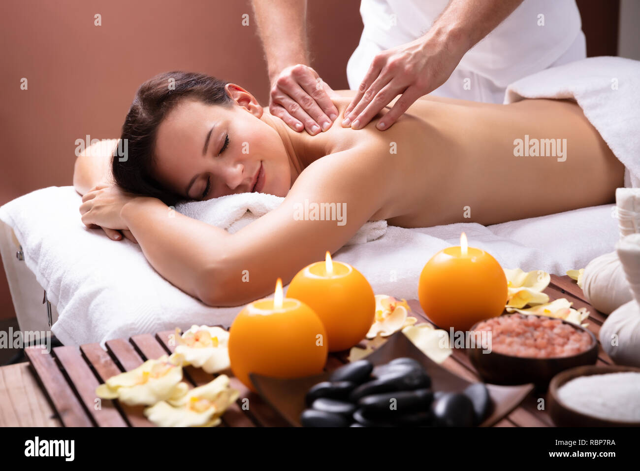 La main du thérapeute de sexe masculin massage de l'épaule de jeune femme détendue Banque D'Images
