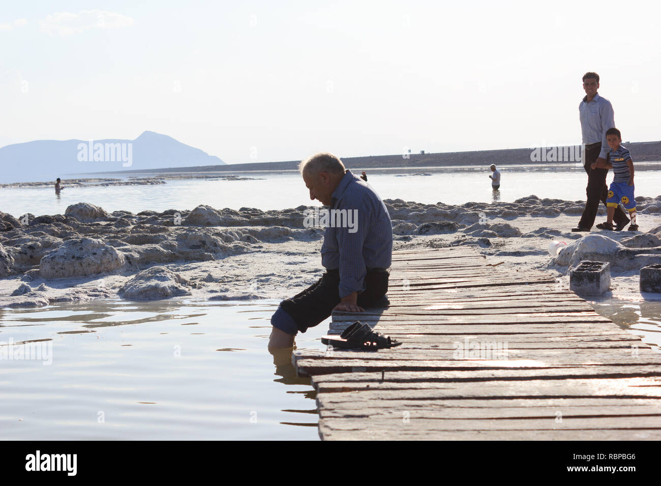 Un vieil homme assis sur la plage du lac d'Orumieh sel, province de l'Ouest, l'Iran Banque D'Images