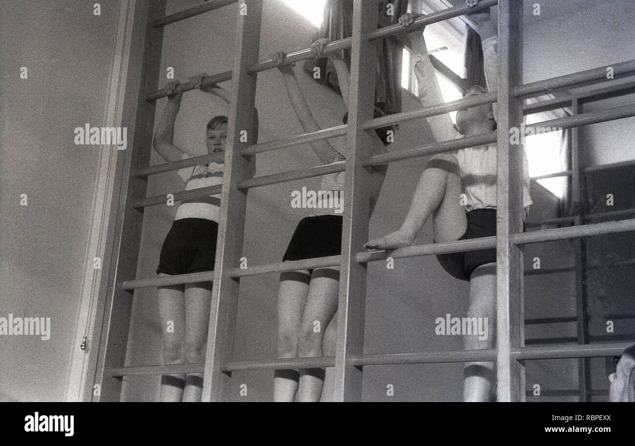 Années 1950, historiques, écolières dans vêtements de sport à l'école secondaire du comté sur une piscine d'escalade en bois à une classe PE, England, UK. Banque D'Images