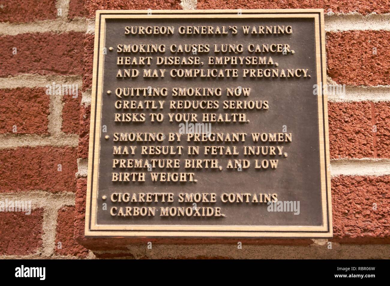 Plaque d'avertissement du chirurgien général au sujet des dangers du tabagisme sur un mur de brique à New York City Banque D'Images