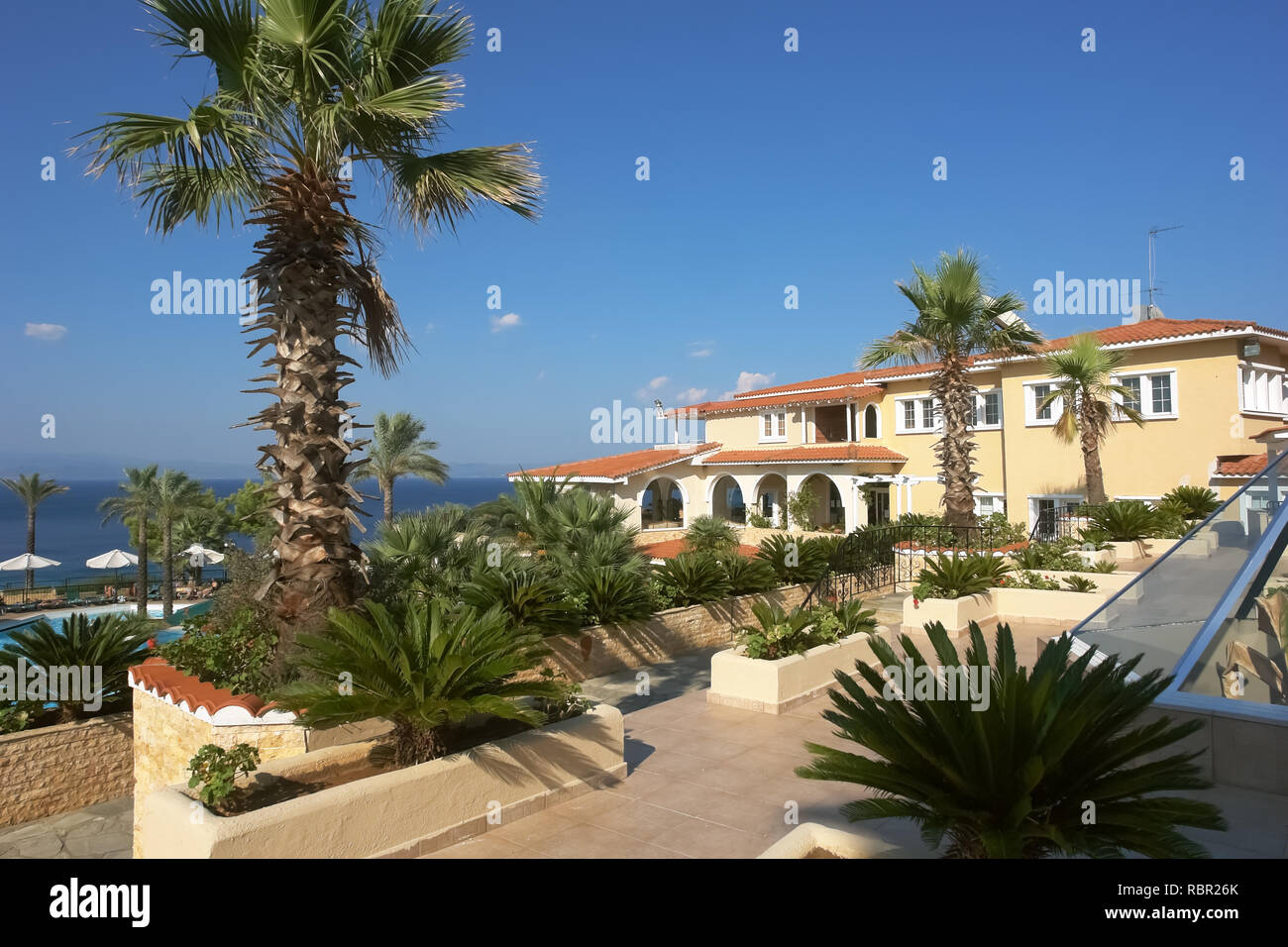 Athitos, Grèce - septembre 3, 2013 : vue sur le bâtiment jaune, le bleu de la mer et le vert des palmiers dans l'hôtel, péninsule de Kassandra, Grèce. Banque D'Images