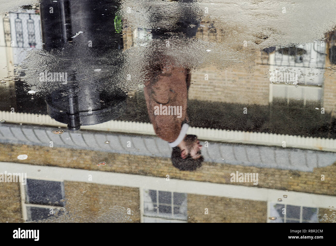 La réflexion d'un homme dans une flaque sur le trottoir - Brighton, Sussex (Royaume-Uni) Banque D'Images