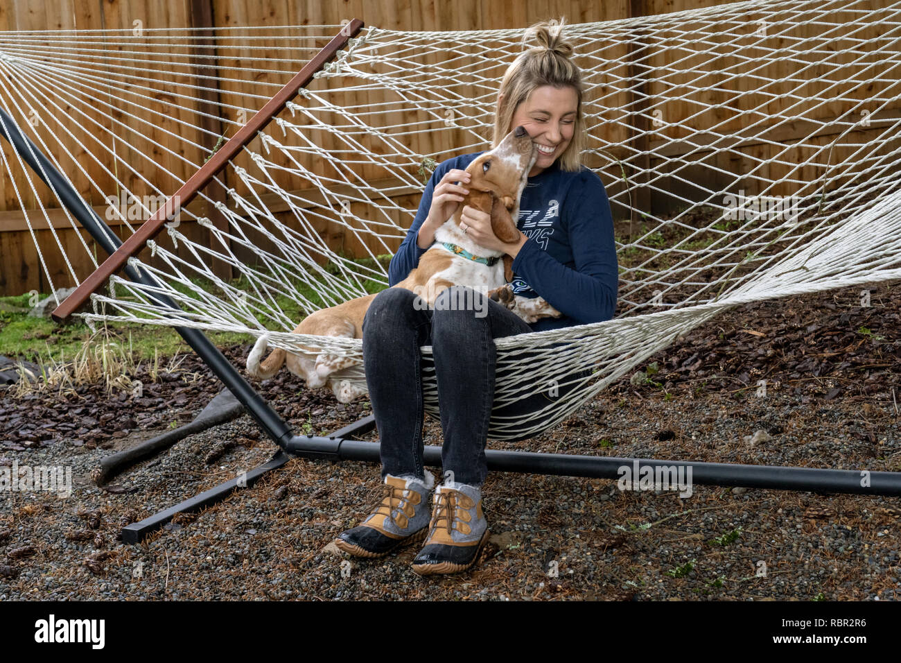 Renton, Washington, USA. Femme est affectueux avec ses cinq mois chiot Basset Hound 'Elvis' comme ils se reposer dans un hamac. Banque D'Images