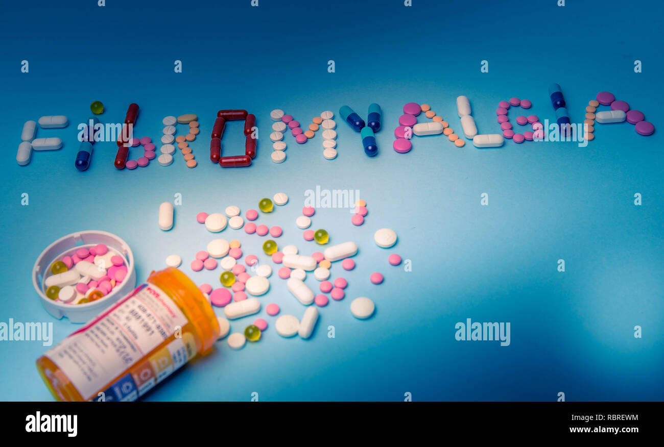 Le mot Fibromyalgie écrit par médicaments colorés, pilules, médicaments, comprimés, gélules sur un fond bleu Banque D'Images