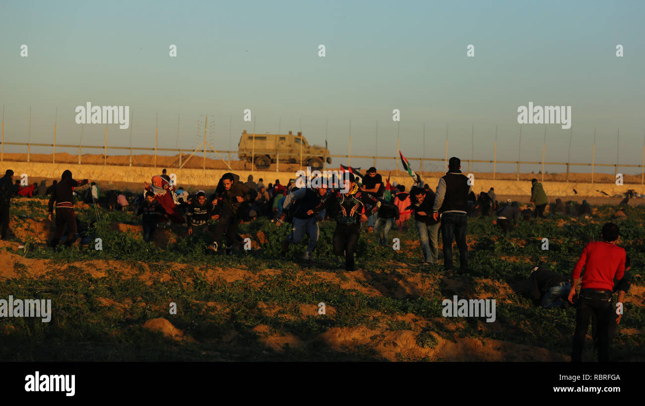 Des manifestants palestiniens ont vu se mettre à couvert à partir de la ligne de front de la confrontation après avoir tiré à balles réelles sur eux pendant la manifestation de Palestiniens se sont affrontés avec les forces israéliennes au cours des manifestations sur le mur entre Gaza et Israël à l'est de Khan Yunis. Banque D'Images