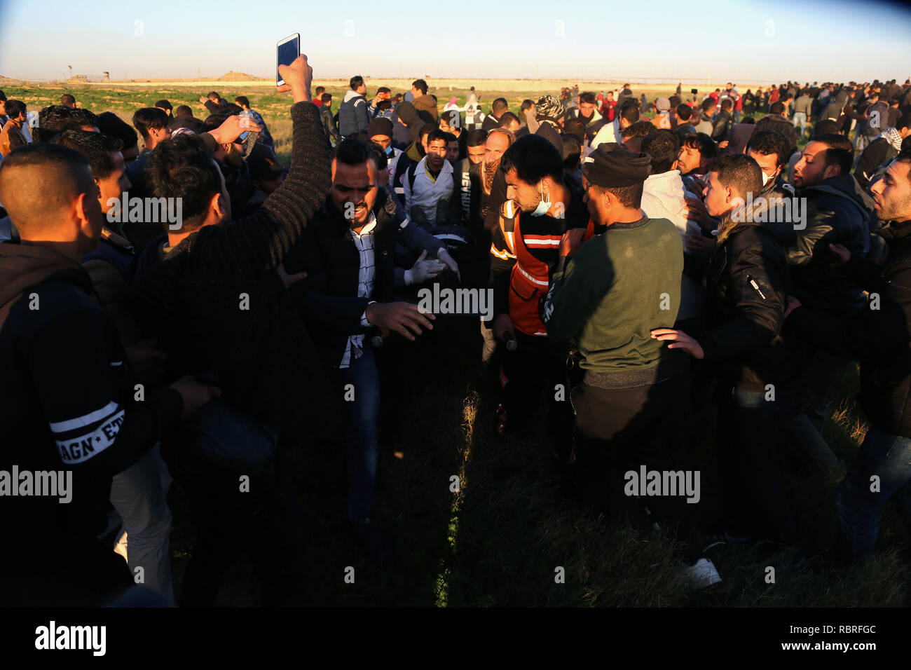 Le personnel médical est vu porter une personne blessée qui a été touchée par une bombe de gaz dans la tête directement au cours de la protestation. Les Palestiniens se sont affrontés avec les forces israéliennes au cours des manifestations sur le mur entre Gaza et Israël à l'est de Khan Yunis. Banque D'Images
