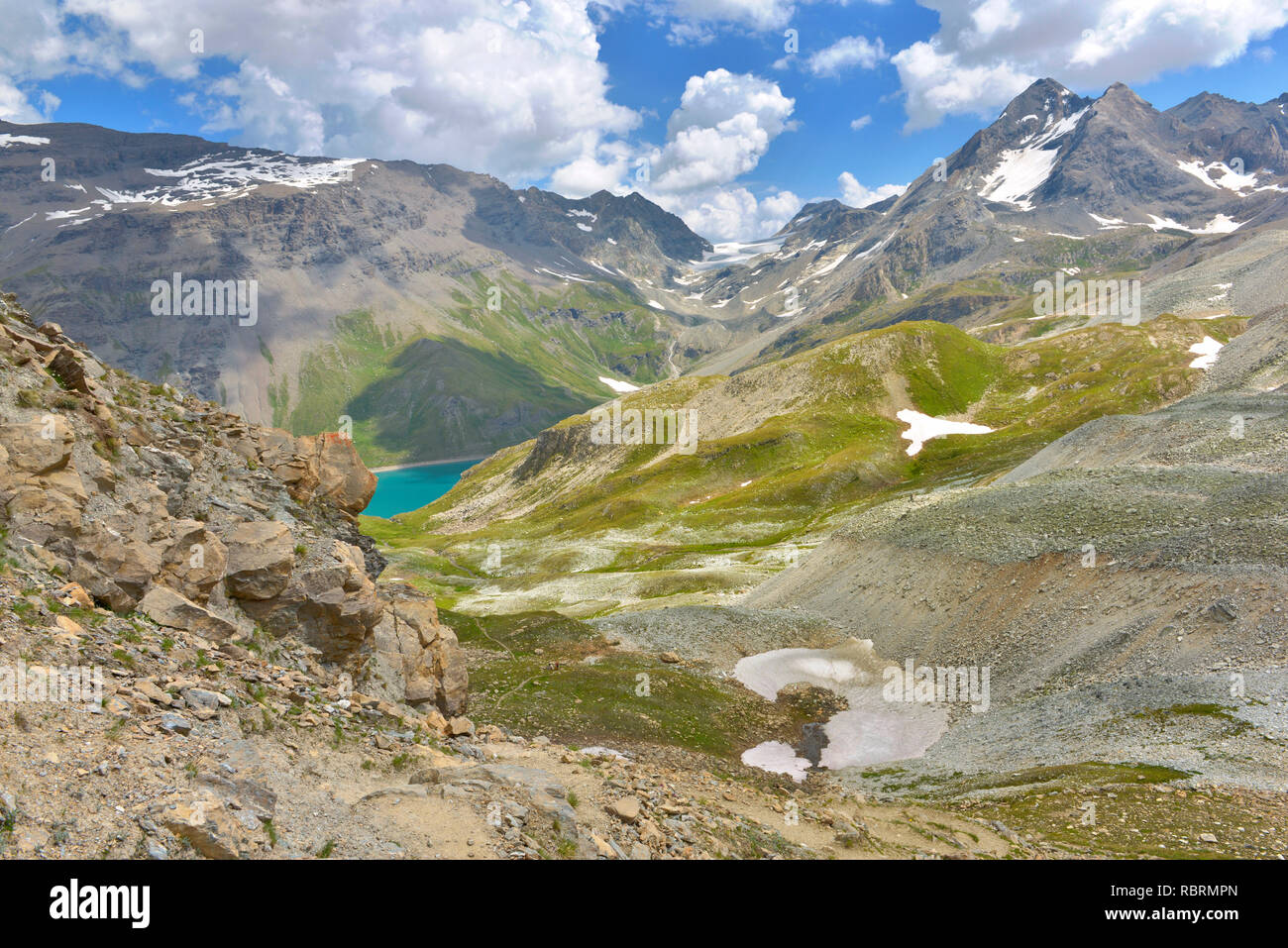 La montagne alpine sous ciel nuageux avec vue sur un lac bleu au loin Banque D'Images