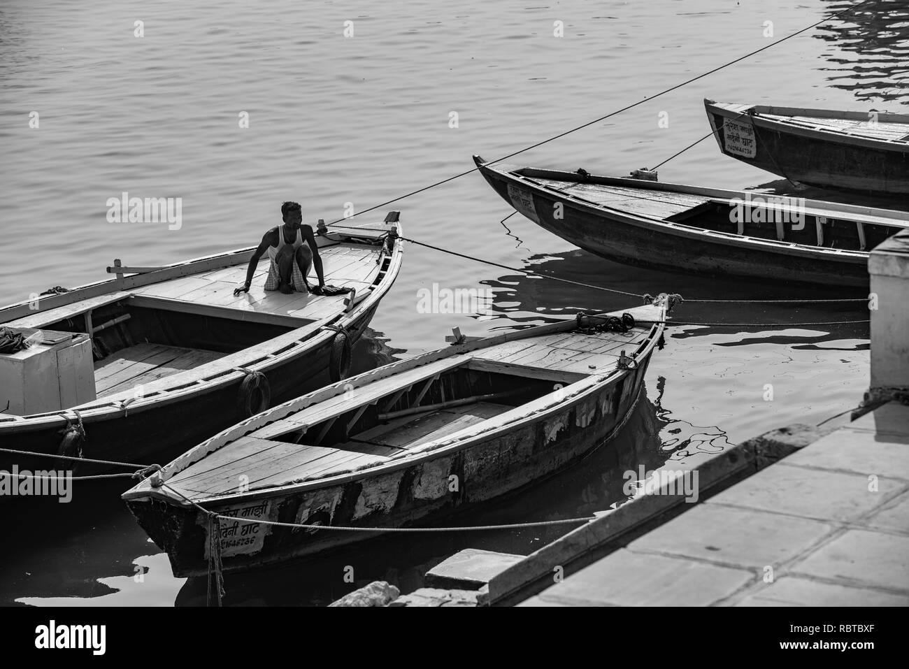 Composition photo noir et blanc de quatre bateaux sur le Gange avec un homme qui fait l'objet se trouve - à Varanasi, Inde. Banque D'Images