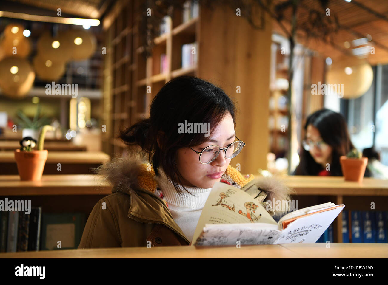 Chongqing, China's Chongqing. Jan 11, 2019. Une femme lit un livre dans une bibliothèque dans le Beicang créatif culturel & quart sud-ouest de la Chine, Chongqing, du 11 janvier 2019. Beicang créatifs culturels & Trimestre, situé dans le quartier de Jiangbei du sud-ouest de la municipalité de Chongqing, est rénové à partir d'un ancien entrepôt de textile. Le trimestre se compose de plusieurs sections, dont une bibliothèque publique, entreprises de loisirs et de zones de bureau. Il conserve l'architecture industrielle de style des années 1950 et 1960, attirant de nombreuses personnes à visiter. Credit : Wang Quanchao/Xinhua/Alamy Live News Banque D'Images