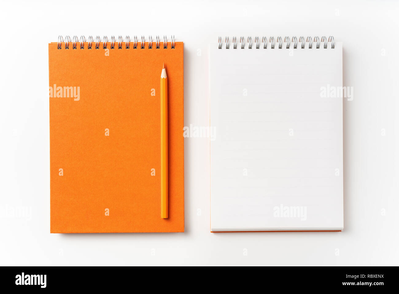 Concept design - Vue de dessus d'orange carnet à spirales, Page blanche et le crayon isolé sur maquette pour l'arrière-plan Banque D'Images