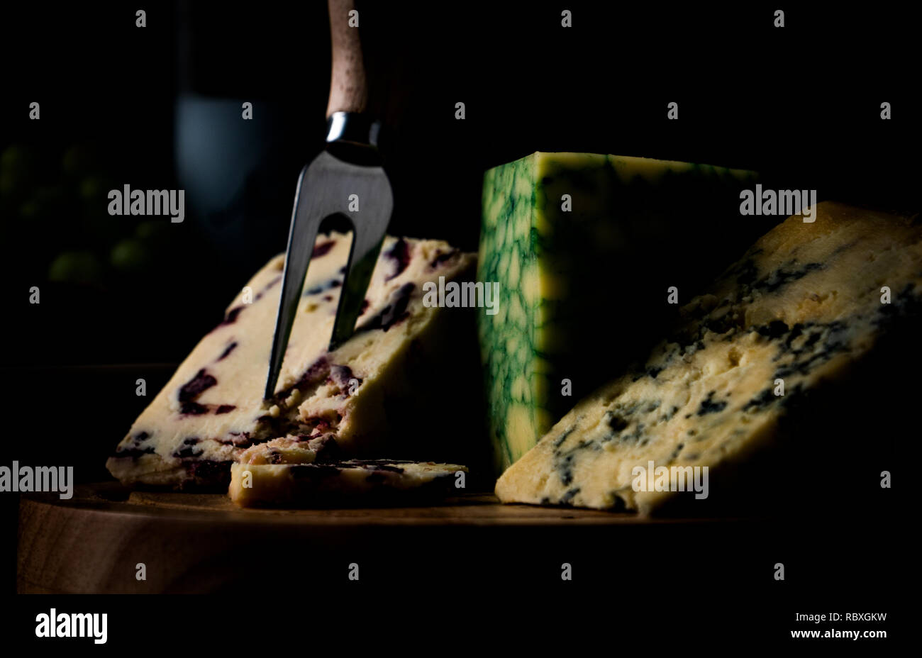 L'humeur sombre plateau à fromage avec sélection Wensleydale, Stilton et Sage Derby contre un fond sombre Banque D'Images