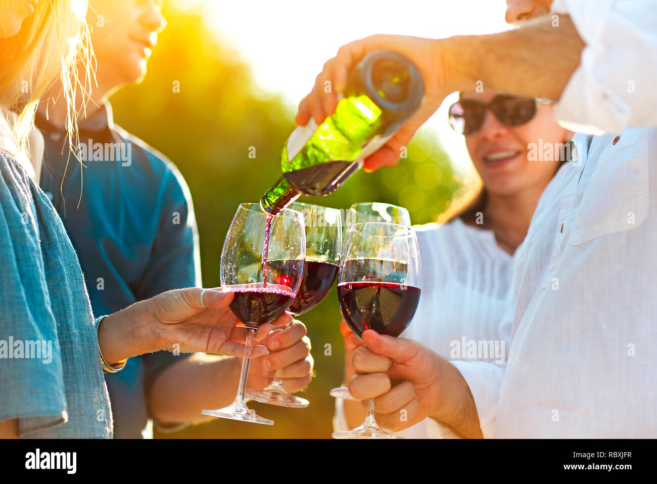 Les gens à l'extérieur du vin partie. Fête du vin. Man pouring red wine in à l'wineglasses Banque D'Images