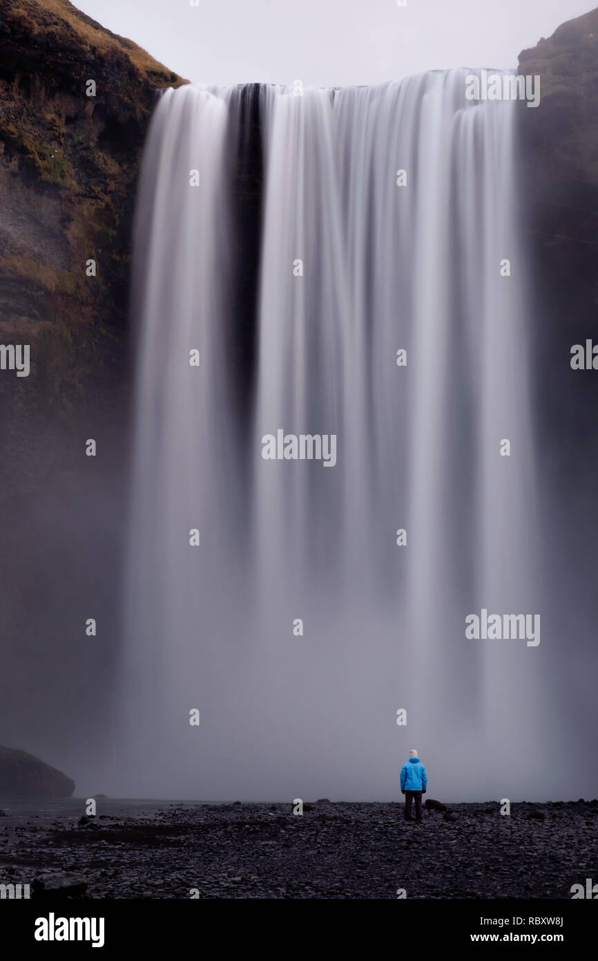 Une longue exposition de la personne regardant cascade Skogafoss en Islande Banque D'Images