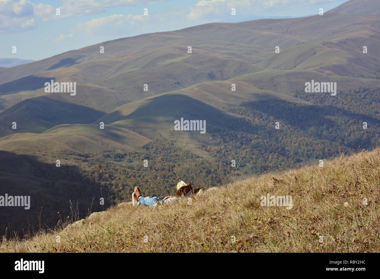 Jeune homme dans des vêtements de cow-boy reste sur les montagnes.Traveler bénéficiant d'une vue panoramique au cours de la randonnée, avec en arrière-plan magnifique paysage de montagne. Banque D'Images