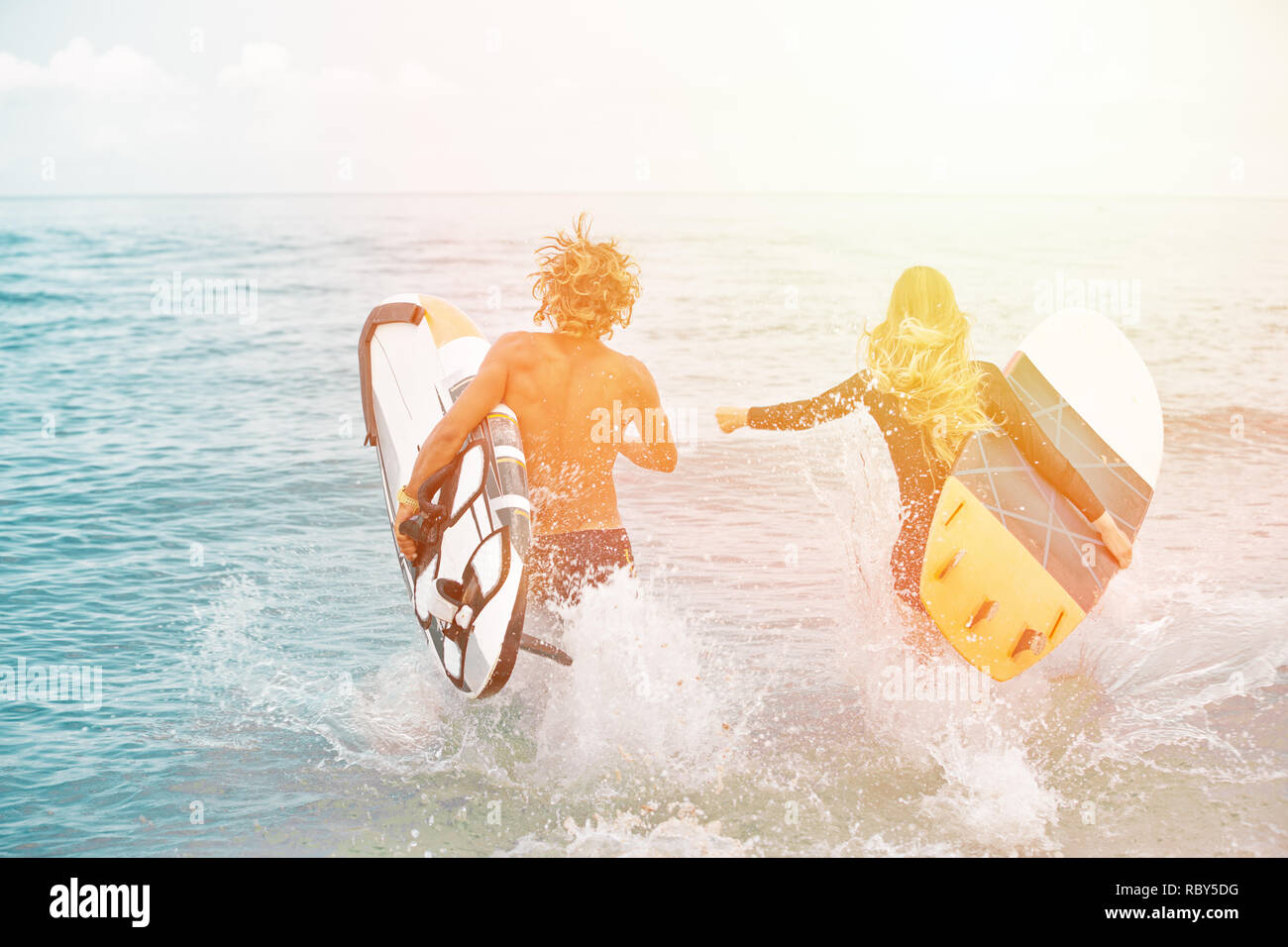 Les surfeurs à la plage- Smiling couple de surfers marche sur la plage et s'amuser en été. Sport extrême et vacances Banque D'Images