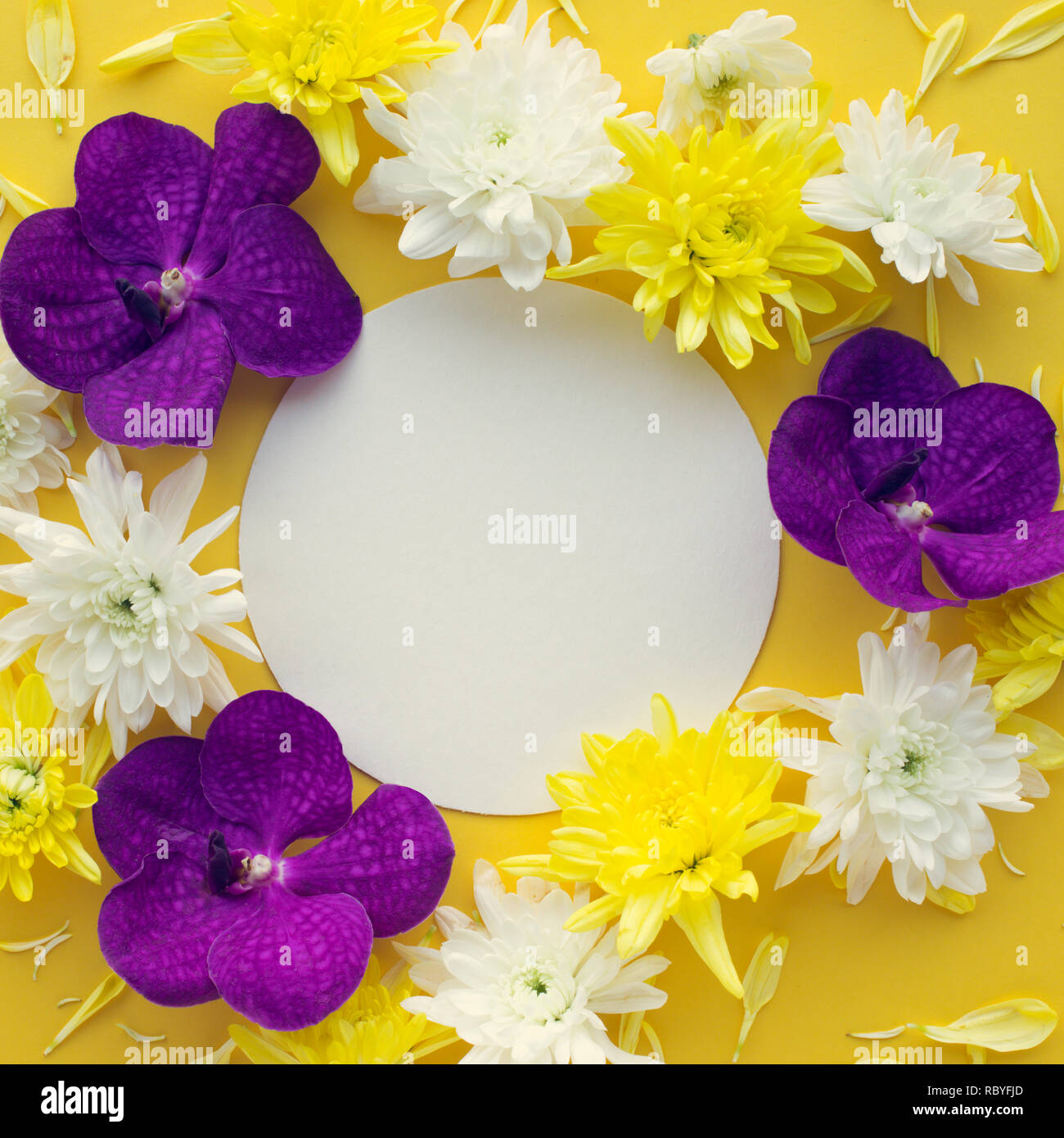 Vue de dessus de l'espace blanc à fleurs colorées sur fond ton jaune Banque D'Images