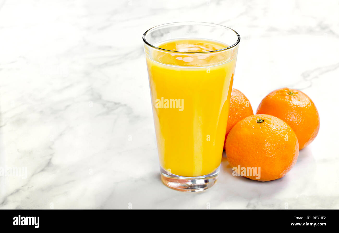 Jus d'orange dans un verre, vue du dessus. Jus de fruits sains sur fond de marbre blanc ou de pierre. Banque D'Images