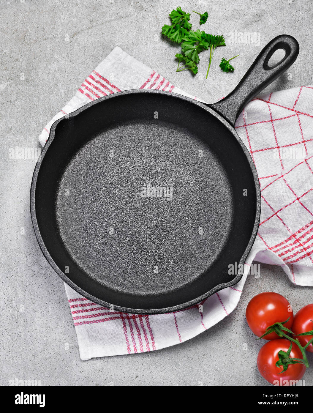 Poêle en fonte sur un fond de béton grunge avec copie espace. Poêle de fer vide, vue de dessus ou high angle shot avec les herbes et les tomates.poêle en fonte sur un Banque D'Images