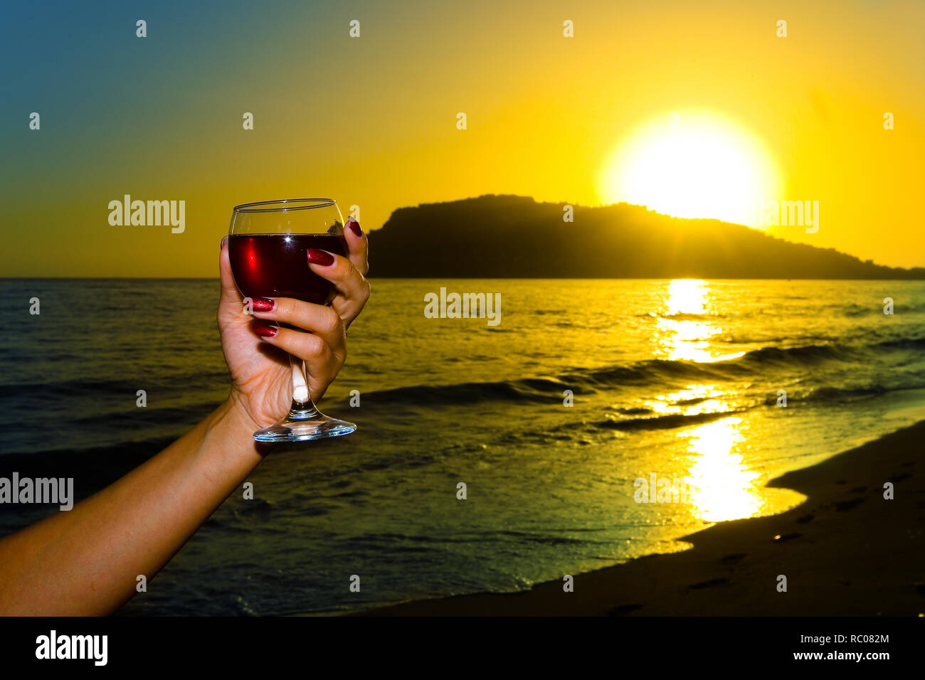 Un verre de vin dans une main de femme élégante sur l'arrière-plan d'un coucher de soleil. Alanya turc. Banque D'Images