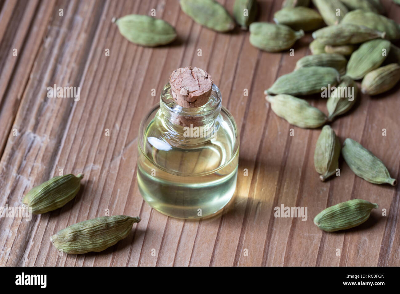 Une bouteille d'huile essentielle avec les graines de cardamome Banque D'Images