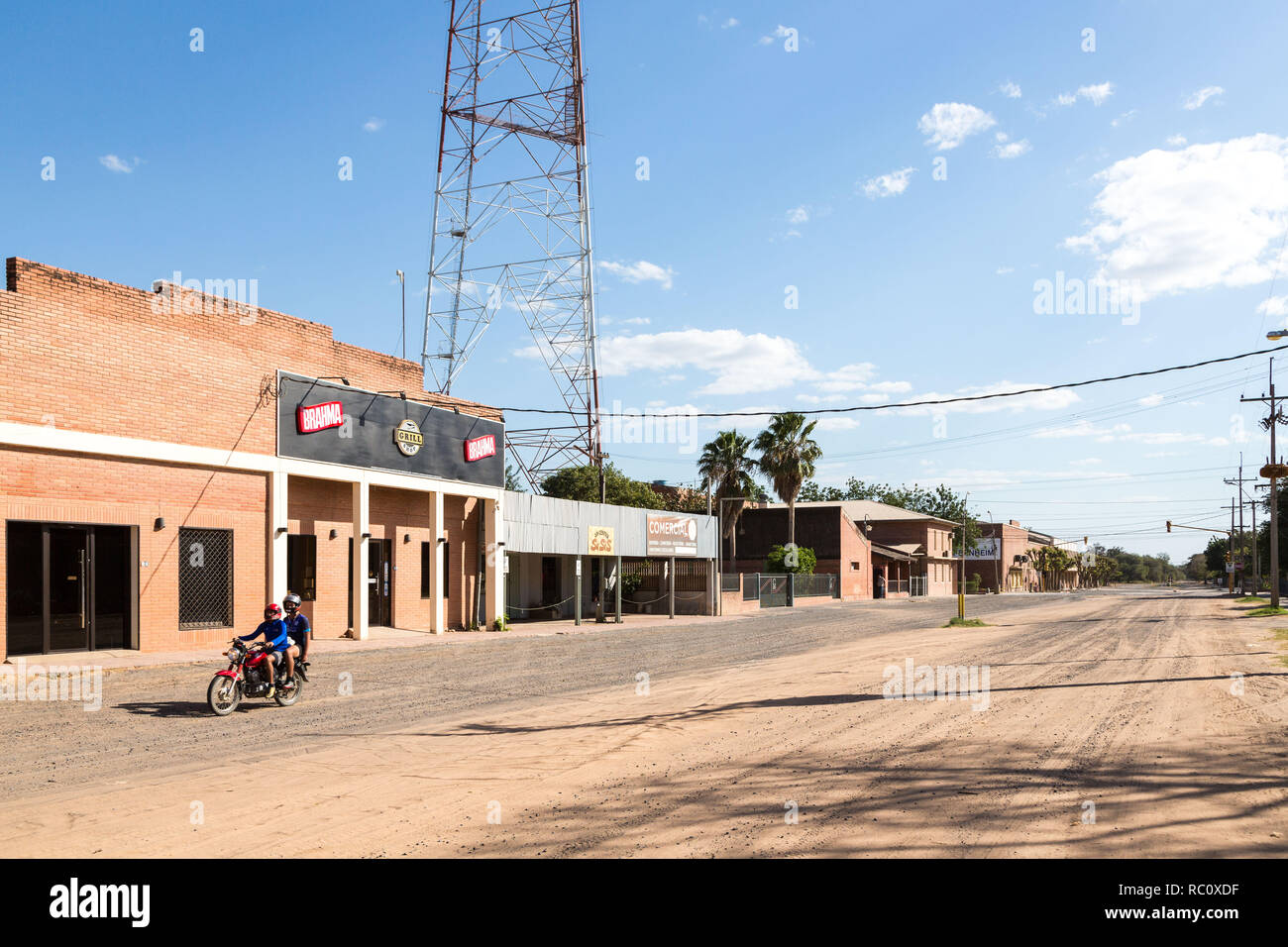 Centre-ville de Filadelfia, Ministère Boqueron, Gran Chaco, au Paraguay. Colonie mennonite Deutsch. Deux mecs sur un vélo en descendant la rue poussiéreuse de sable Banque D'Images