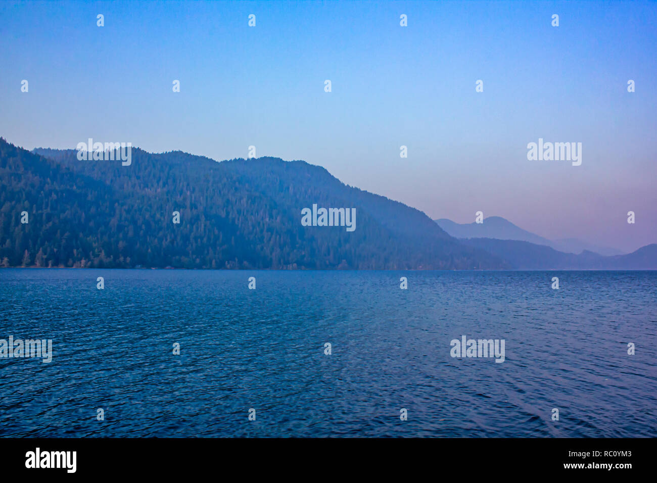 Montagnes derrière sur le lac en été, le soir au coucher du soleil dans l'eau reflète les couleurs Banque D'Images