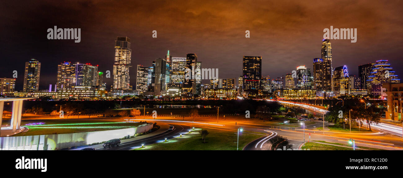 Panorama de l'Austin Texas skyline at night avec l'architecture du voyant et ciel nuageux dans l'arrière-plan et les voitures filant en premier plan Banque D'Images